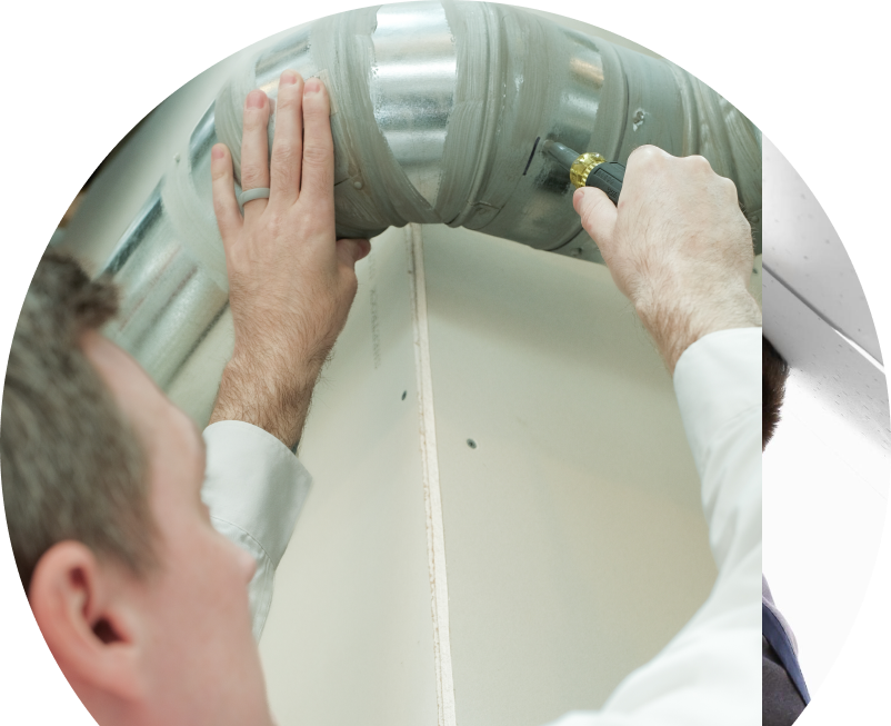 Shines HVAC technician inspecting and tightening a joint on a sealed metal air duct, performing maintenance work during an air duct cleaning task.