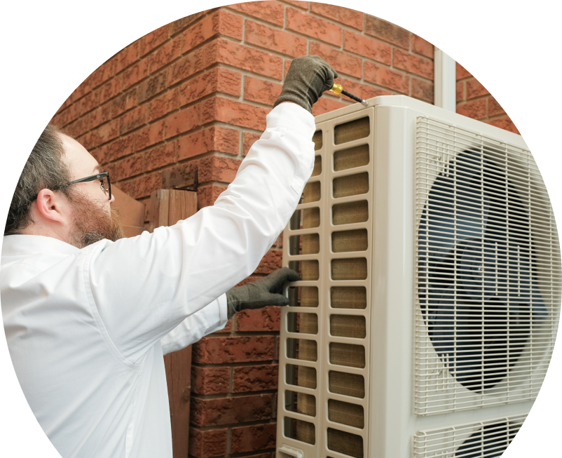 Shines HVAC specialist using a screwdriver to complete a heat pump installation beside a brick wall. Shines HVAC specialist using a screwdriver to complete a heat pump installation beside a brick wall.