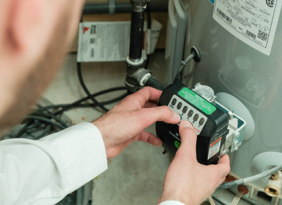 A Shines technician adjusts the control module on a residential water heater, verifying proper operating settings. A Shines technician adjusts the control module on a residential water heater, verifying proper operating settings.